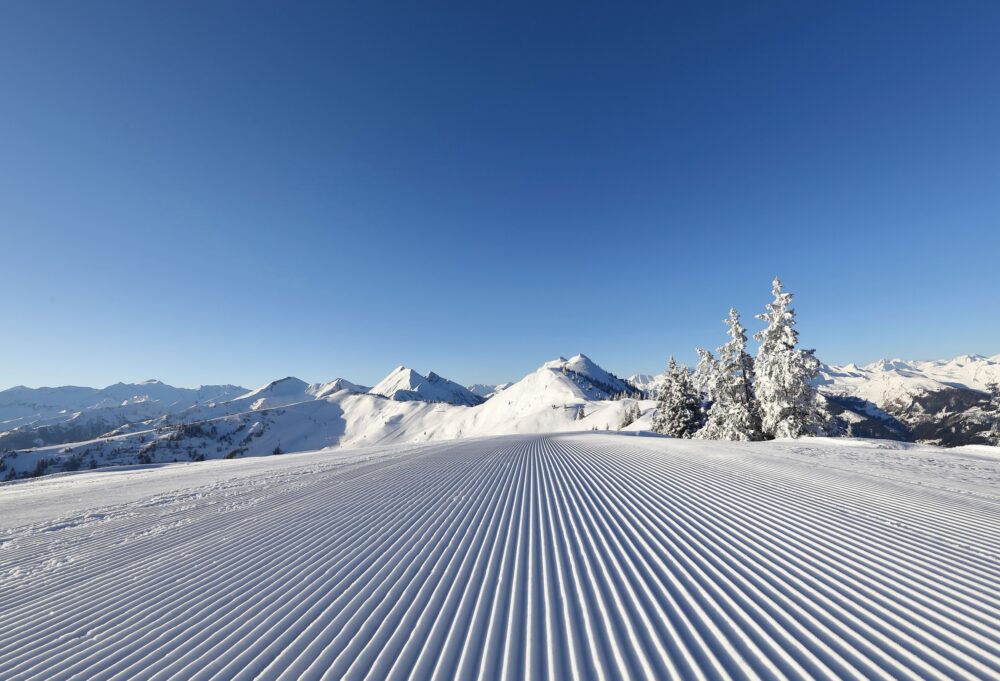 Frisch präparierte Piste mit Rillen. Im Hintergrund die Berge im Skigebiet Großarltal.