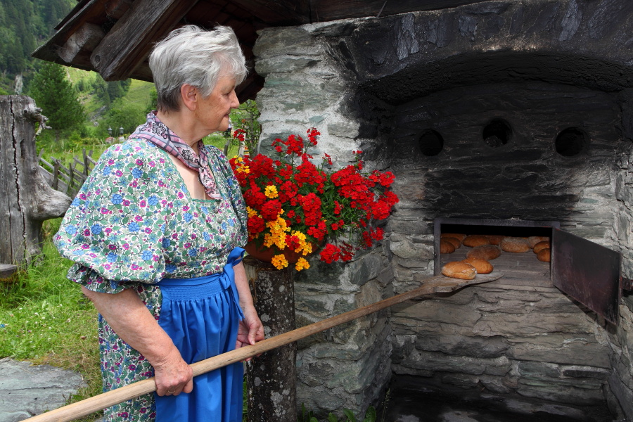 Marianne holt das fertige Brot aus dem Steinofen